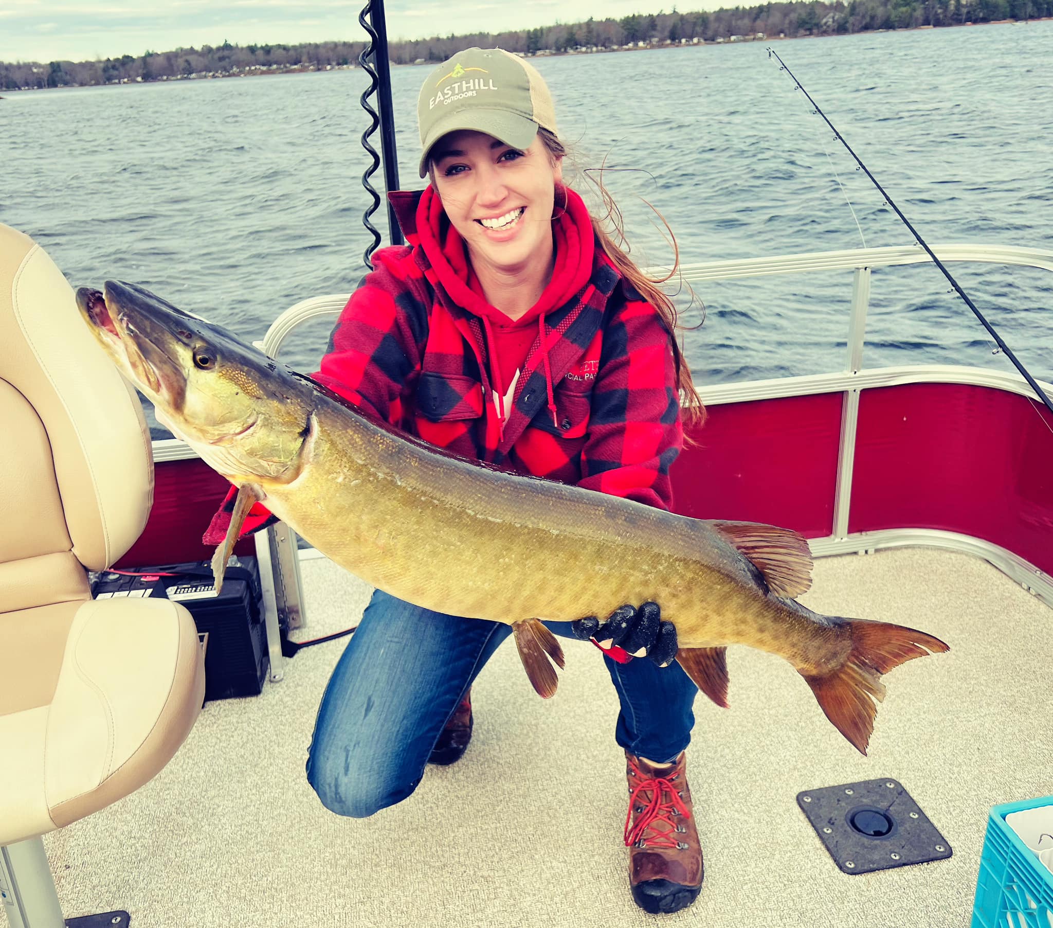 Person holding a large fish on a boat on the water