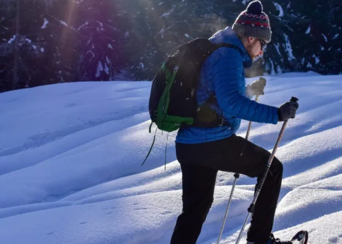 Person walking with snowshoes in snow outdoors on a sunny winter day