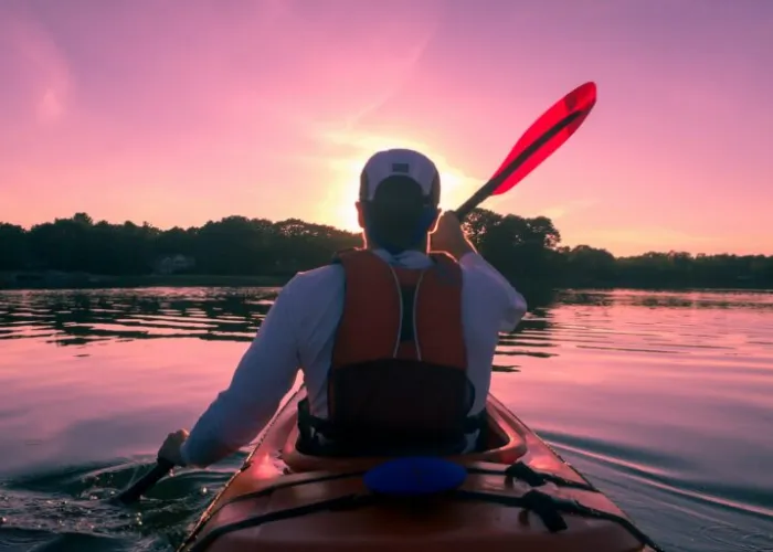 A person paddling in a kayak on a calm lake