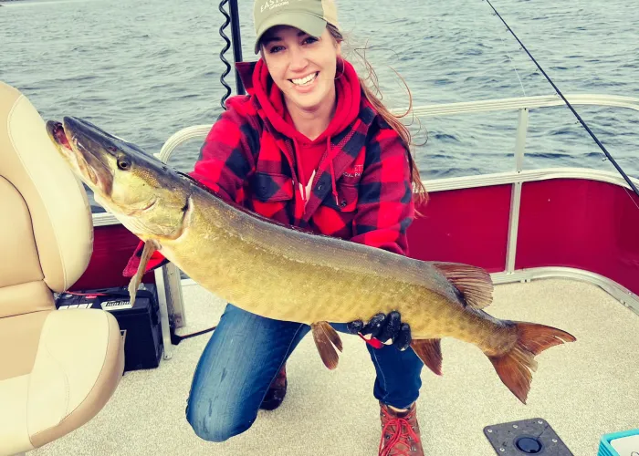 Person holding a large fish on a boat on the water