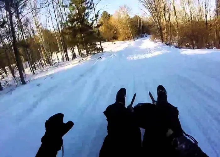 Person on a sled going down hill in the snow on a homemade luge track